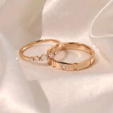 Pair of rose-gold rings—half-eternity five-diamond band beside brushed bezel band on satin